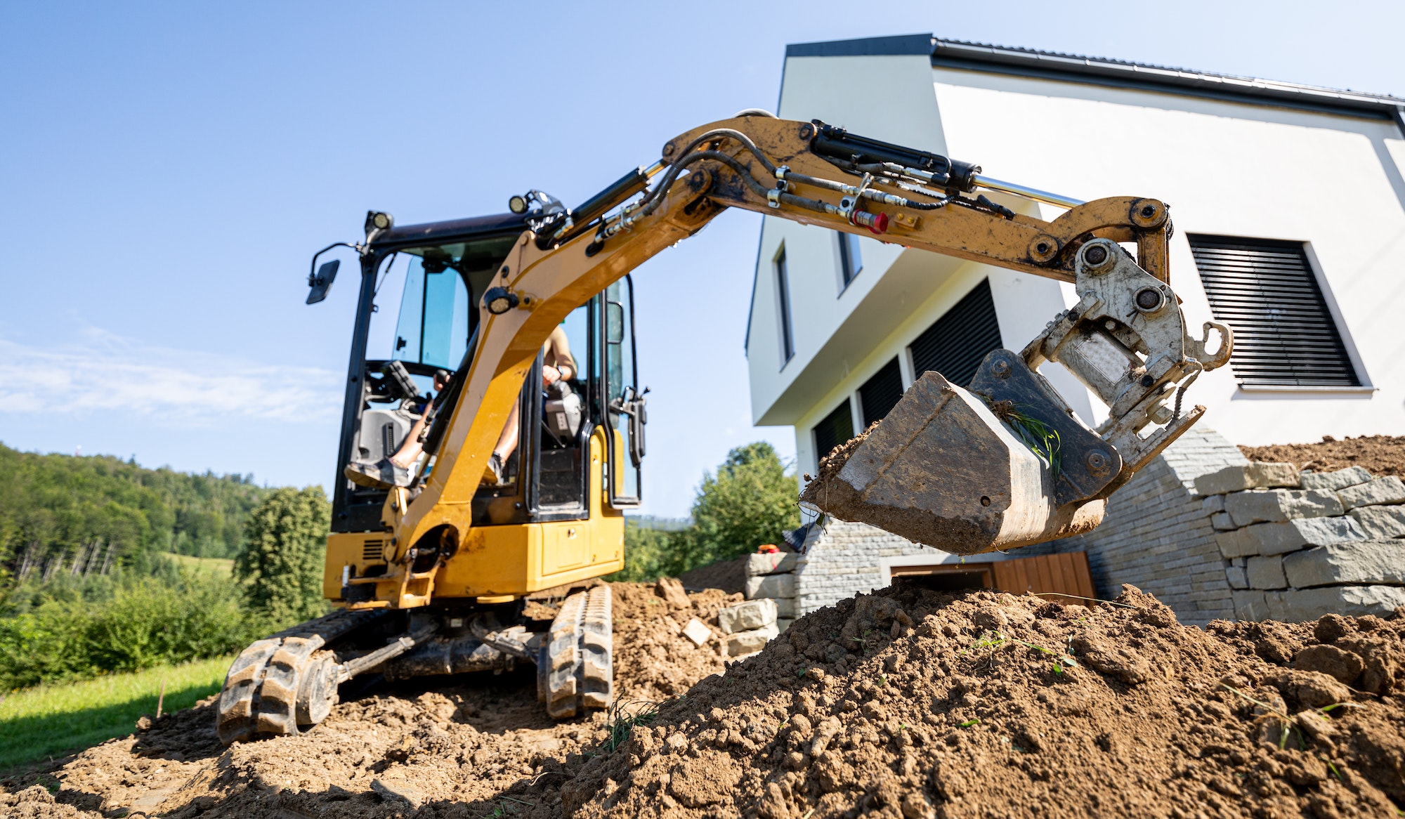 Mini excavator digging preparing ground under home garden